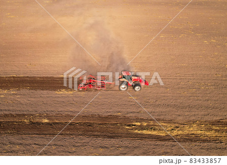 Soil Tillage in farmers country. Red Tractor on cultivating field work.  83433857