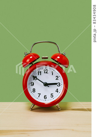 traditional red alarm clock on a green background traditional red alarm clock on a green background 83434908