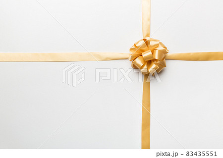 Top view of gold ribbon rolled and yellowbow isolated on colored background. Flat lay with copy space 83435551
