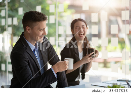Friendly male leader laughing at group business meeting, happy young businesswoman enjoying fun conversation with partner, smiling business coach executive talking to colleague Friendly male leader laughing at group business meeting, happy young businesswoman enjoying fun conversation with partner, smiling business coach executive talking to colleague 83437358