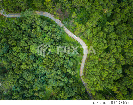 Aerial view of car on the road cut throug green forest in the highland mountains in Chiang Rai province, Thailand. The highland of Chiang Rai is a popular destination during the cold weather season. 83438655
