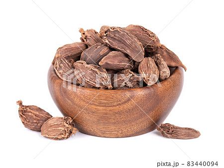 Heap of black cardamom pods in wooden bowl, isolated on white background. Black cardamon seeds. Clipping path. Heap of black cardamom pods in wooden bowl, isolated on white background. Black cardamon seeds. Clipping path. 83440094