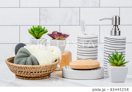 Herb soap, shower sponge and shampoo pump bottle inside a bright bathroom. 83445258