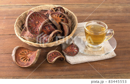 The Bael fruit juice in a glass and dried Bael fruit placed on the wooden 83445553
