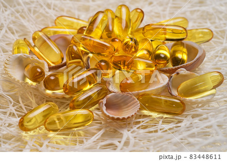 Omega-3 fish fat oil capsules on the small shells and fishing net. EPA and DHA are essential fatty substances that our bodies need on a daily basis. 83448611