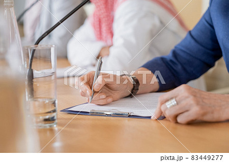 Close-up of unrecognizable woman making notes in paper while participating in conference Close-up of unrecognizable woman making notes in paper while participating in conference 83449277