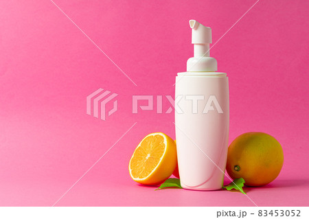 Cosmetic bottle with sliced citrus fruits on bright pink background Cosmetic bottle with sliced citrus fruits on bright pink background 83453052