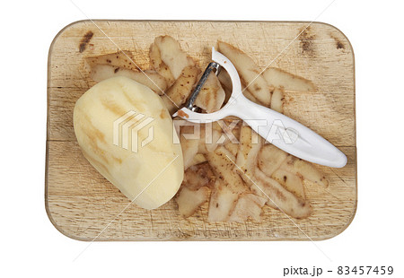 Raw potato peeled on a wooden chopping board with peeler cut out and isolated Raw potato peeled on a wooden chopping board with peeler cut out and isolated 83457459