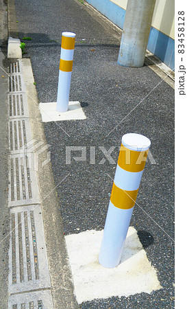横断歩道手前にある車止めのポールがある風景 83458128