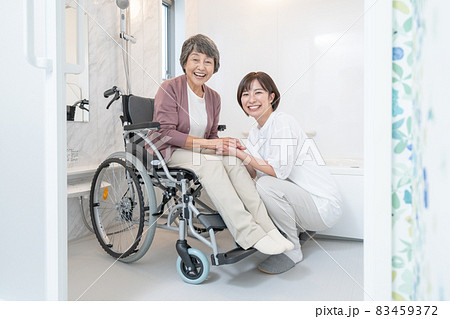 お風呂場で車椅子に乗る老婆と介護する孫のポートレート 83459372