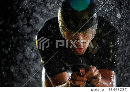 triathlon athlete riding bike fast on rainy night triathlon athlete riding bike fast on rainy night 83463227