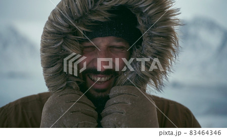 man at winter in stormy weather wearing warm fur jacket 83464346