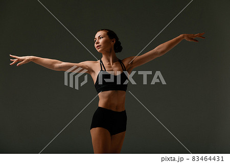 Emotional Female Ballet Dancer in Body Suit and Posing in Dance in Various Poses Against Gray Background Emotional Female Ballet Dancer in Body Suit and Posing in Dance in Various Poses Against Gray Background 83464431