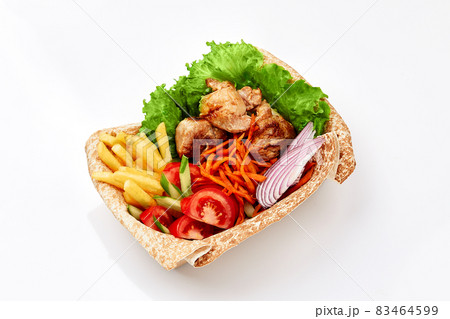 chicken kebab on thin pita bread with sauce with French fries and salad on white background. Fast food chicken kebab on thin pita bread with sauce with French fries and salad on white background. Fast food 83464599