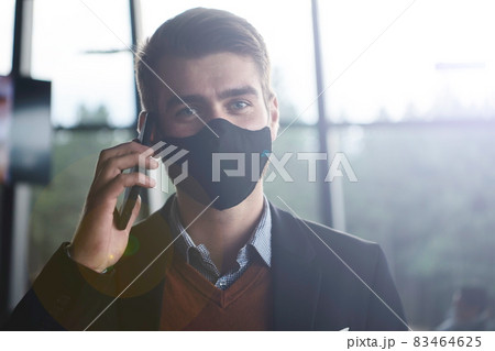 business man wearing coronavirus medical face mask while using smartphone business man wearing coronavirus medical face mask while using smartphone 83464625