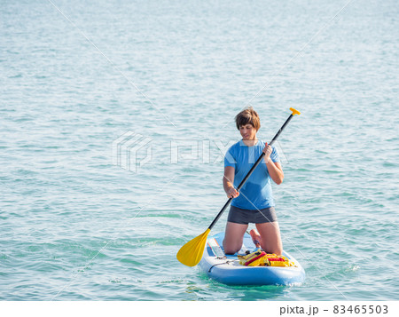Handsome paddle boarder. Sportsman on knees paddling on stand up paddleboard. SUP surfing. Active lifestyle. Outdoor recreation. Vacation on seaside. Handsome paddle boarder. Sportsman on knees paddling on stand up paddleboard. SUP surfing. Active lifestyle. Outdoor recreation. Vacation on seaside. 83465503