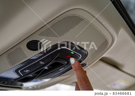 female driver's finger presses the sos button on the ceiling panel of a modern car female driver's finger presses the sos button on the ceiling panel of a modern car 83466681