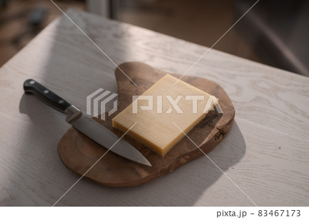 Small block of aged cheese on wood board with knife 83467173