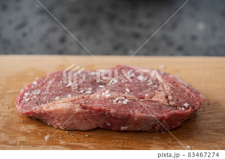 Raw ribeye steak spiced and ready to cook on oak board 83467274