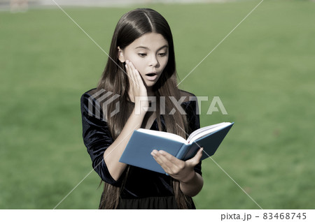 Learn to discover. Surprised child read book outdoors. Learn to discover. Surprised child read book outdoors. 83468745