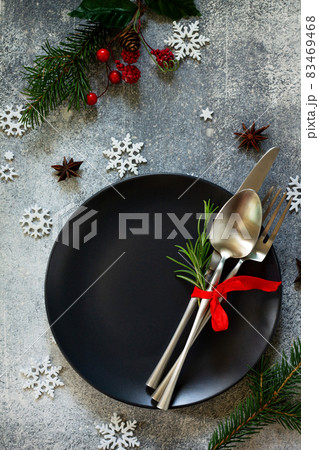 Christmas background. Christmas decoration table. Festive black plate and cutlery with Christmas decor on retro festive table. Top view flat lay. 83469468