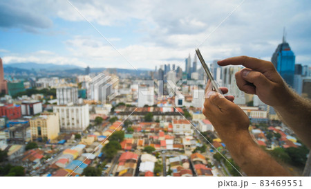 The guy is working with a smartphone on a blurred background. Kuala Lumpur. Hands and phone close up. Malaysia. 83469551