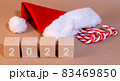 2022 figures on wooden cubes santa Claus hat and candy canes Christmas background in craft style 83469850