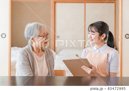 高齢者女性と話す女性スタッフ（メモ） 83472995