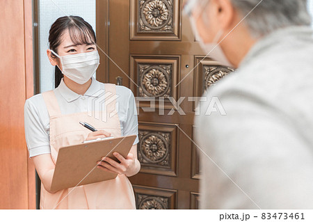 高齢者住宅に訪問する女性（書類・マスク） 83473461