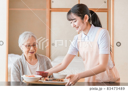 食事をする高齢者女性と女性スタッフ(配膳) 食事をする高齢者女性と女性スタッフ(配膳) 83473489