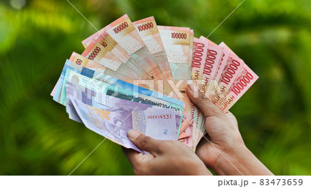 The girl is holding Indonesian money. Indonesian rupee. The girl is holding Indonesian money. Indonesian rupee. 83473659