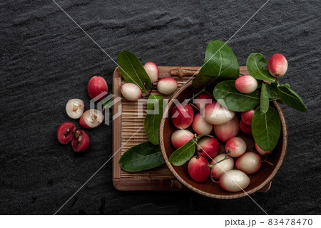 Bengal-Currants, Carandas-plum or Karonda fruit (Carissa carandas L.) sour taste fruit in Wooden cup on wicker. 83478470