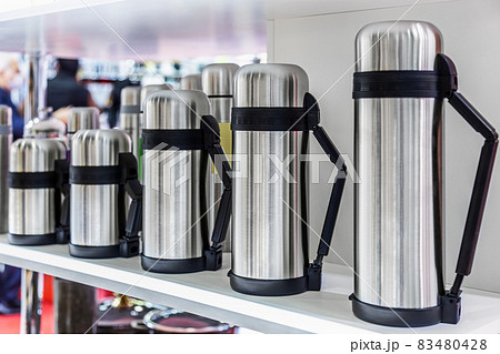 stainless metal thermos flasks are on the counter 83480428