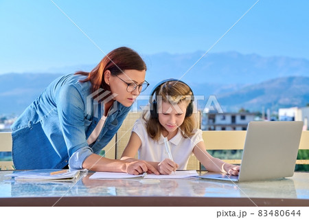 Mother helping her daughter to a schoolgirl with online studies Mother helping her daughter to a schoolgirl with online studies 83480644