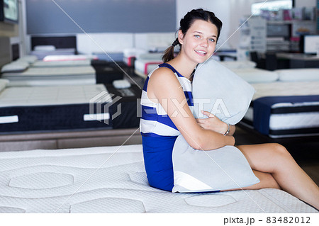 Female sitting with pillow on mattress Female sitting with pillow on mattress 83482012