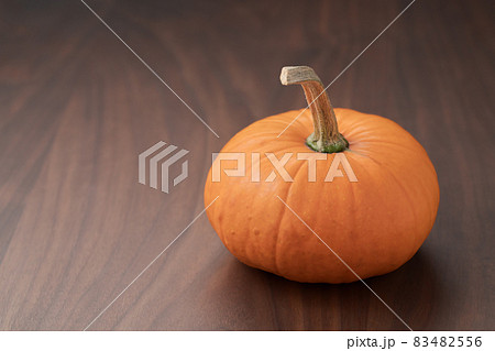 Small orange pumpkin on black walnut table with copy space Small orange pumpkin on black walnut table with copy space 83482556