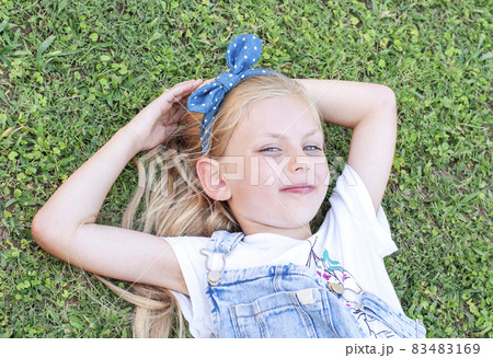 Little girl lying on green grass Little girl lying on green grass 83483169