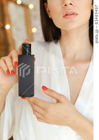 Beautiful fresh young woman applying cream or body wash on hand from dispenser indoors Beautiful fresh young woman applying cream or body wash on hand from dispenser indoors 83483497