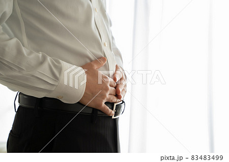 スーツ姿の男性が腹部に手をあてている様子 83483499