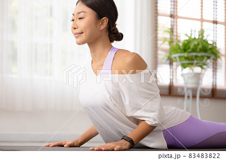 n woman practising yoga, Cobra exercise, Bhujangasana stance, working out, and wearing sportswear. 83483822