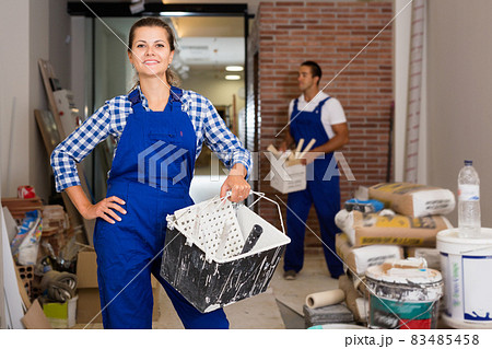 Man and woman in work overalls doing finishing work in room of public space 83485458