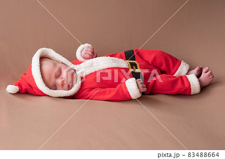 Newborn girl dressed in santa claus costume yawning being tired. 83488664
