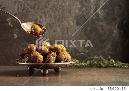 Spicy green olives are poured with olive oil with spices. 83490136