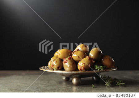 Spicy green olives in olive oil on a black background. 83490137