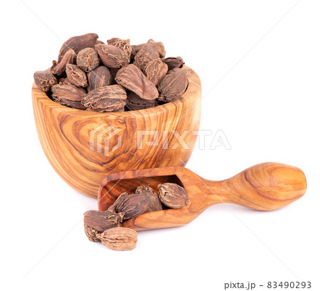 Heap of black cardamom pods in olive bowl and scoop, isolated on white background. Black cardamon seeds. Clipping path. 83490293