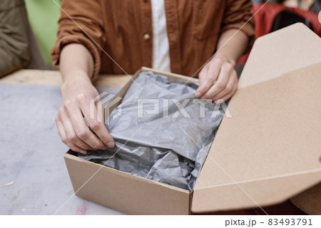 Close-up of woman packing things in box to deliver parcel to the customer 83493791