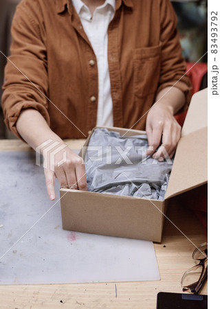 Close-up of seller packing parcel into the cardboard box for delivery 83493792