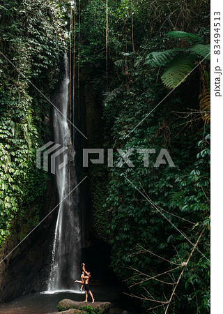 Couple at a tropical waterfall. The couple travels to the island of Bali in Indonesia. A woman and a man at a beautiful waterfall. Vacation on a tropical island. Traveling couple at the waterfall 83494513