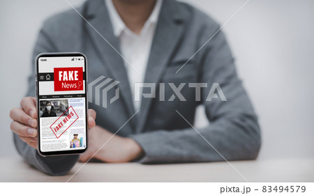 Fake News online on smartphone concept, businessman reading Fake news or articles about covid-19 in a smartphone screen application, media technology ,Online fake news on a mobile phone or computers. 83494579
