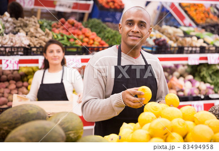 Friendly seller posing with yellow lemons in local supermarket 83494958